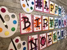 the wall is decorated with happy birthday letters and paintbrushes for kids to decorate