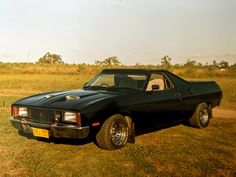 a black car parked on top of a grass covered field