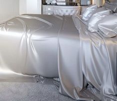 a bed covered in silver sheets and pillows