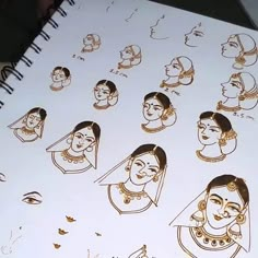 an open notebook with drawings of women's heads and faces on it, all in gold foil