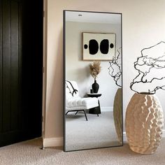 a large mirror in the corner of a room with a vase on the floor next to it