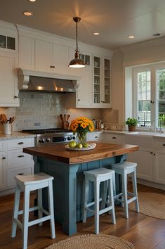 a kitchen with an island and stools in front of the counter top, surrounded by white cabinets