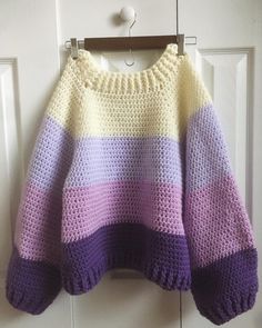 a crocheted sweater hanging on a door