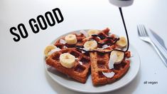 waffles with bananas and syrup are on a white plate next to a fork