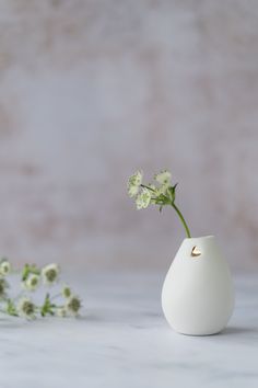 a small white vase with flowers in it