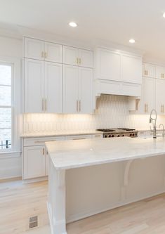 a large kitchen with white cabinets and marble counter tops