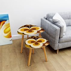 three tables sitting on top of each other in front of a couch and painting next to a chair