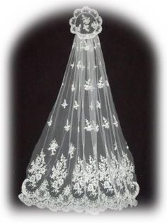 a wedding veil with white flowers on the bottom and lace around the edge, hanging from a black background