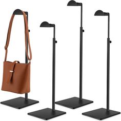 three black and brown stands with two purses on each stand, one holding a tan leather bag