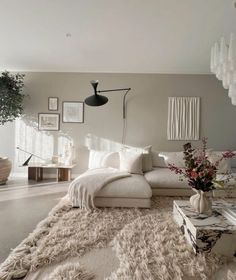 a living room filled with lots of white furniture and decor on top of a rug