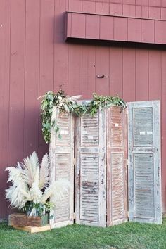 an old wooden door with flowers and greenery in front of a red barn wall