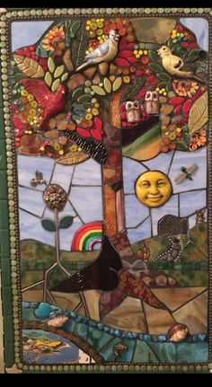 a stained glass tree with birds, flowers and rainbows in the sky above it