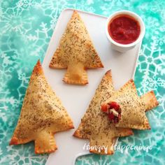 some food is sitting on a plate with sauce in the middle and two triangles shaped like christmas trees