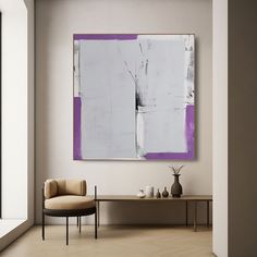 an abstract painting hangs on the wall next to a chair and table in a living room