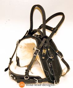 a black and white dog harness with sheepskins on it's back side