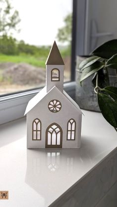 a paper house sitting on top of a window sill