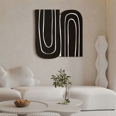 a living room with white furniture and art on the wall