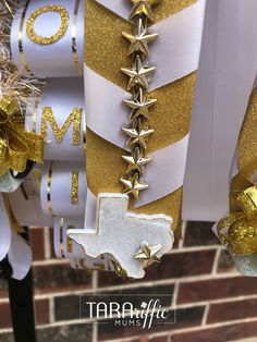 white and gold ribbon with stars hanging from it's side on a pole in front of a brick wall