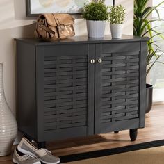 a black cabinet with two doors and some shoes on the floor in front of it