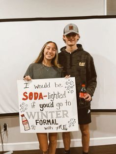 two people standing next to each other holding a sign