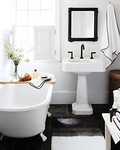 a white bathtub sitting next to a sink in a bathroom under a mirror and window