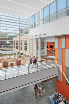 people are walking around in the lobby of an office building with orange and white walls