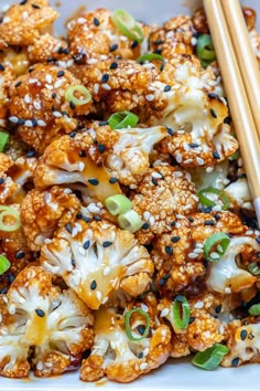 a white plate topped with cauliflower covered in sesame seeds and seasoning sprinkles