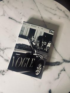 an old fashion magazine sitting on top of a marble table next to a black and white photo