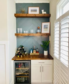 a wine cooler in the corner of a room with shelves above it and pictures on the wall