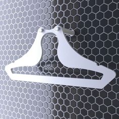 a pair of white clothes hangers on a gray wall with hexagonal tiles