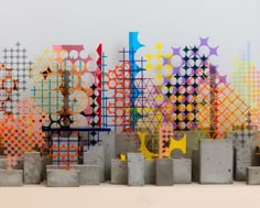 several cement blocks are stacked together in front of a colorful art work on the wall