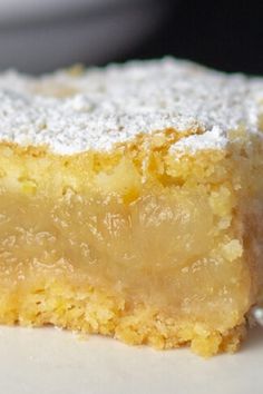 a piece of cake with powdered sugar on top sits on a plate next to a fork