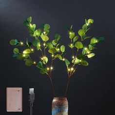 a vase with some lights in it next to a charger and a cell phone