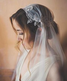 a woman with a veil on her head wearing a wedding dress and hair combs