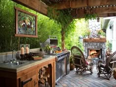 an outdoor kitchen with wood furniture and stone fireplace