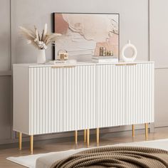 a white and gold sideboard in a living room next to a rug on the floor