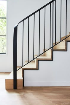 a black and white staircase with wooden handrails in an empty room next to a window