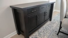 a black cabinet sitting in the corner of a room next to a gray and white rug