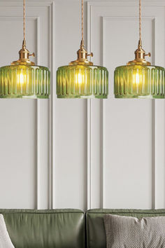 three green glass pendant lights hanging over a couch