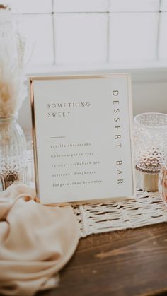 a table topped with glass vases filled with flowers and other items next to a sign that says something sweet