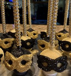 black and gold masquerades with beads hanging from the side on a table