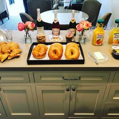 there are donuts and drinks on the counter in this dining room table set up