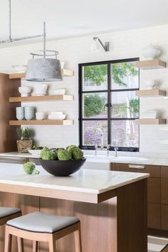 a kitchen with two stools next to a center island and open shelves on the wall