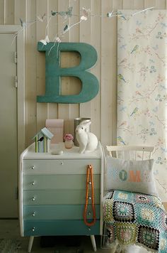 a white dresser sitting next to a wall with a letter b on it's side