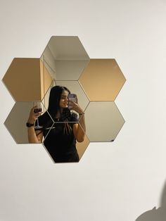 a woman taking a selfie in front of a mirror with hexagonal shapes