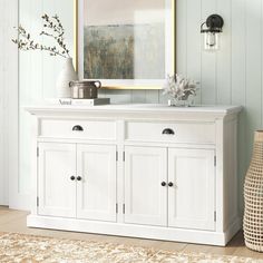 a white sideboard with two doors and drawers in a living room next to a rug