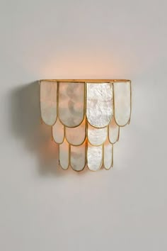 a wall light that is made out of mother of pearles and gold plating