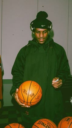 a man holding a basketball in front of several orange balls on a checkered floor