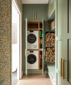 a washer and dryer in a green cabinet with wood stacked on the floor