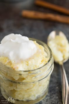 a glass jar filled with whipped cream next to two spoons